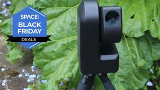 A zwo seestar s50 smart telescope in front of leaves in a garden.