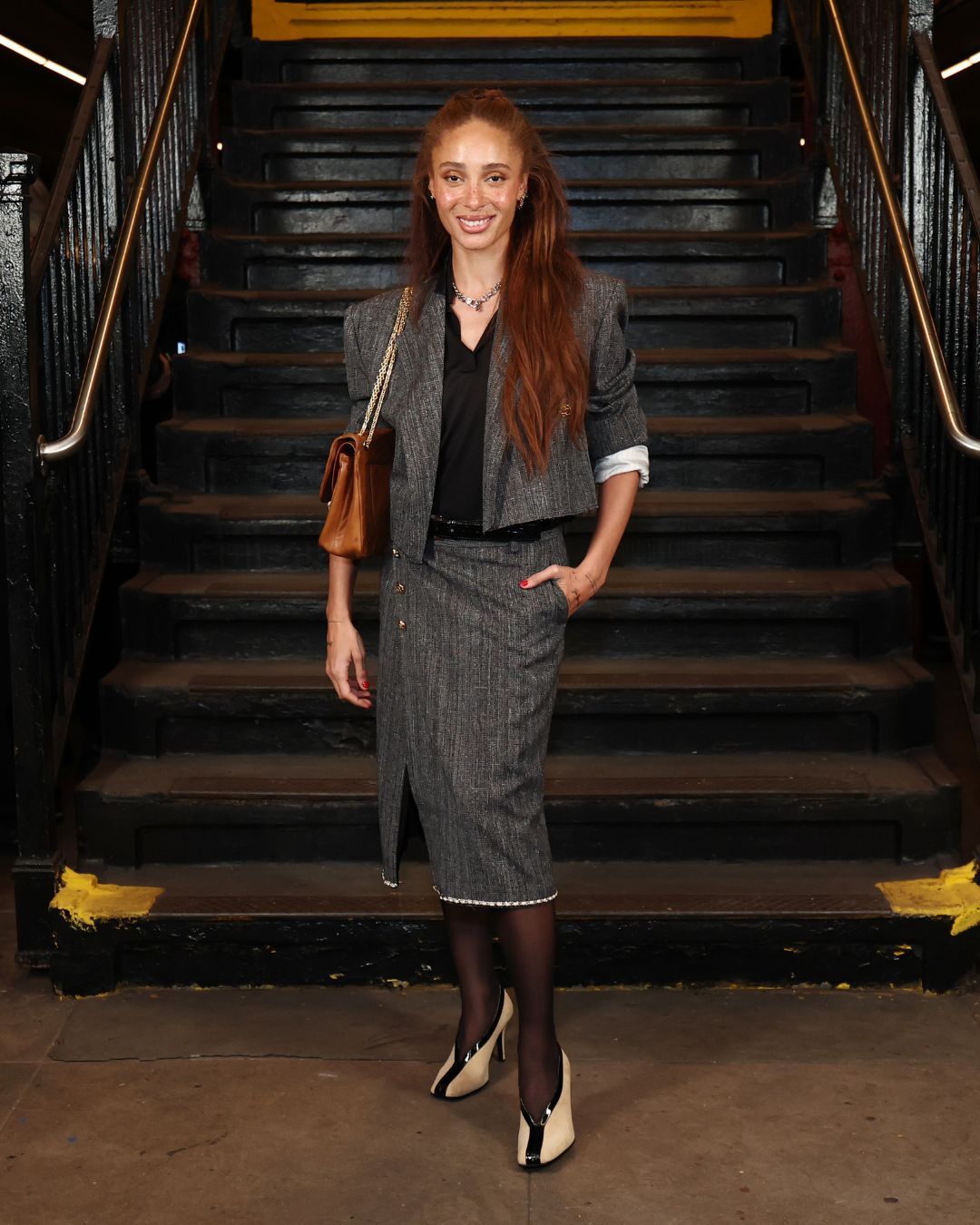 Adwoa Aboah wears a grey pencil skirt with a grey cropped blazer and high-vamp heels at Chanel's Métiers d'art Show in New York