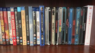 A stack of Blu-ray cases on a wooden shelf