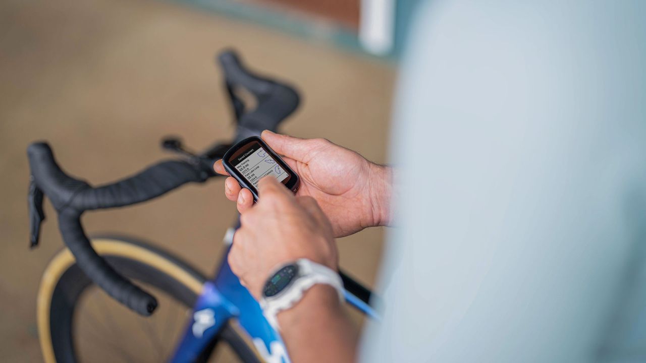 A cyclist holds a Garmin Edge GPS bike computer