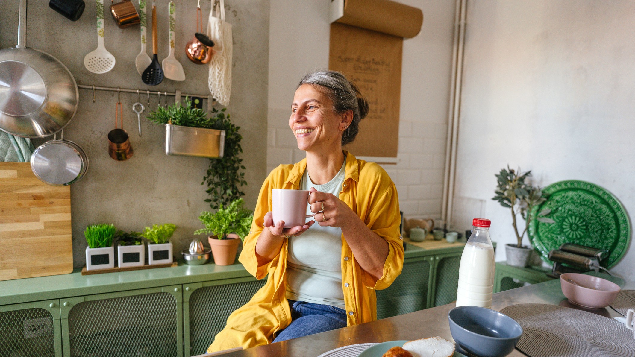 Photo of a woman having a first morning coffee in the kitchen of her apartment.