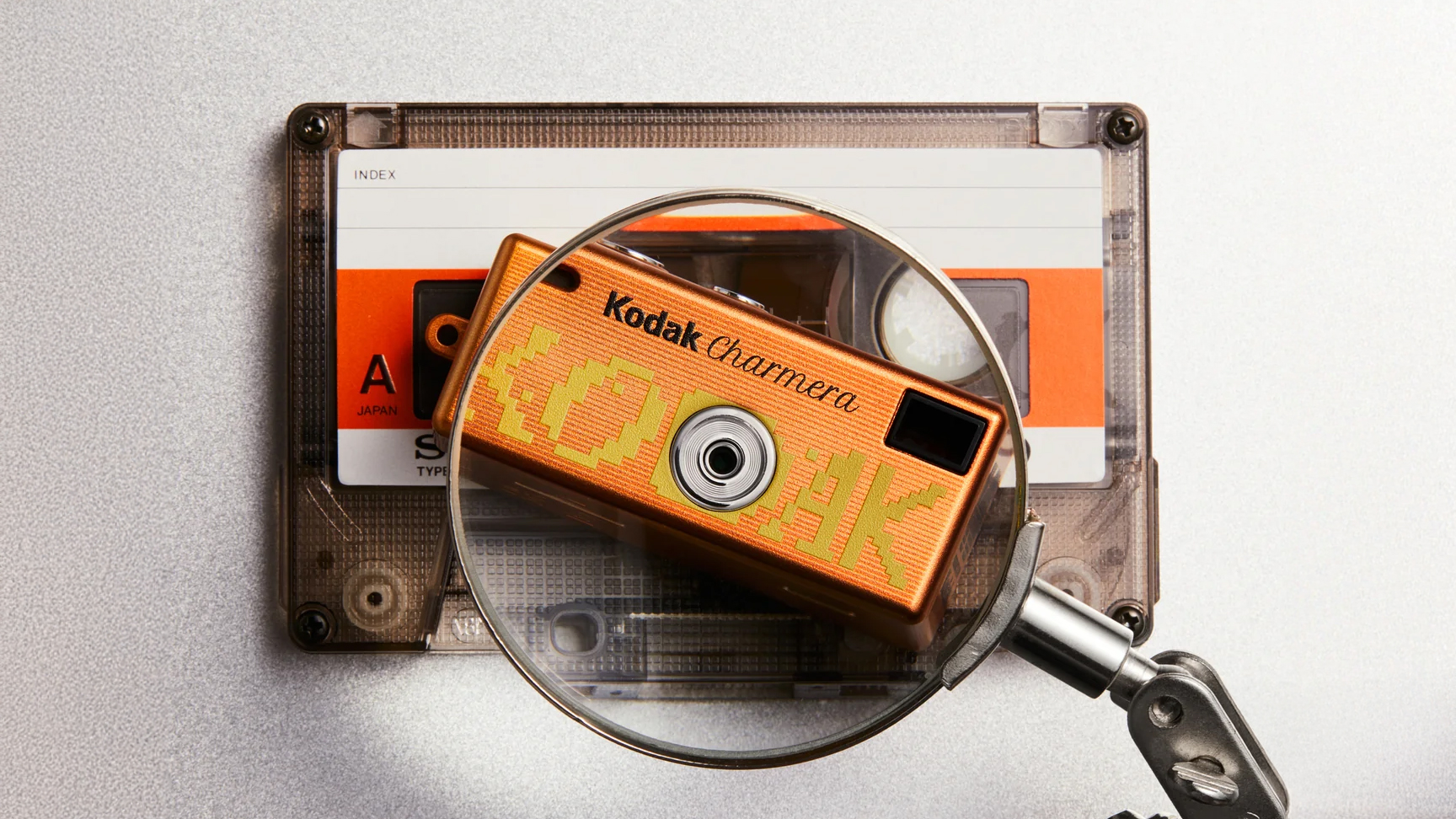 Kodak Charmera Millennium Edition on top of an audio cassette, under a magnifying glass