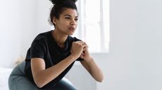 A woman performs a leg workout at home, squatting down and exhaling in a clean white room
