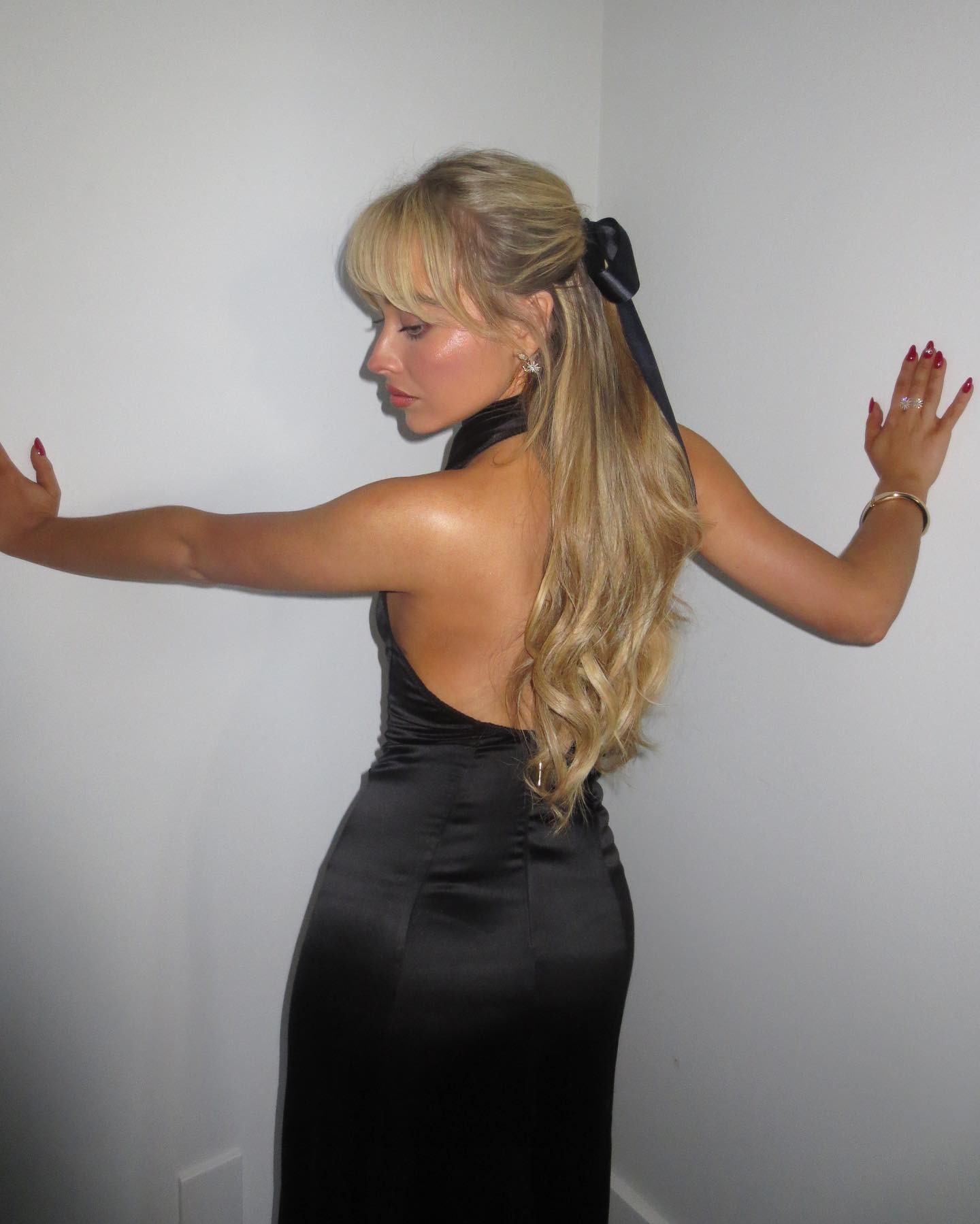 Sabrina Carpenter wearing a half-up half-down hairstyle with a black bow.