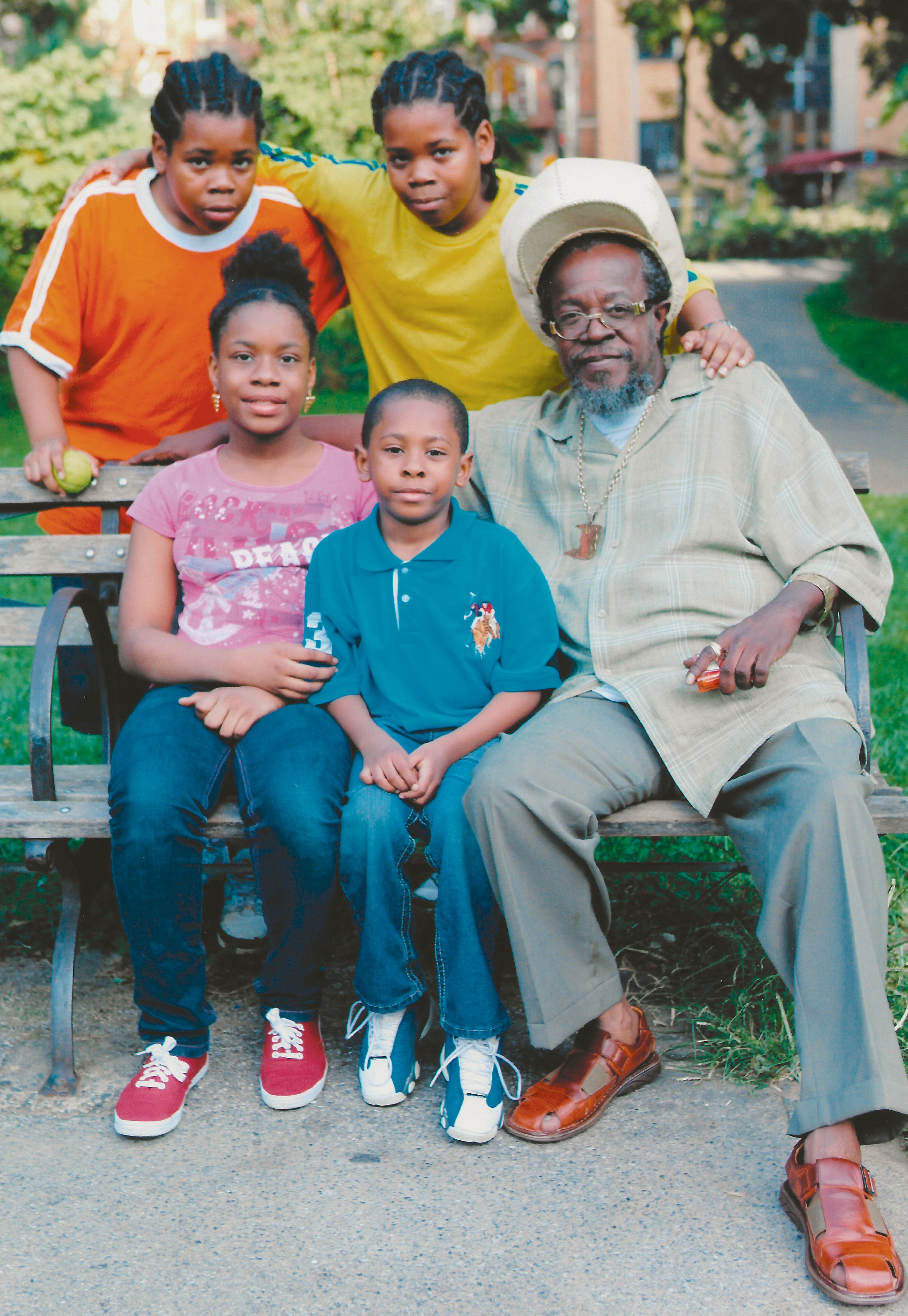 family on a bench and gathered around, posing for photo
