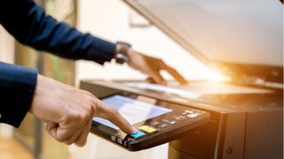 Bedste printer 2022 - To hænder, der betjener en printer/kopimaskine