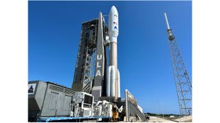 a brown and white rocket rolls toward its launch pad with a blue sky in the background