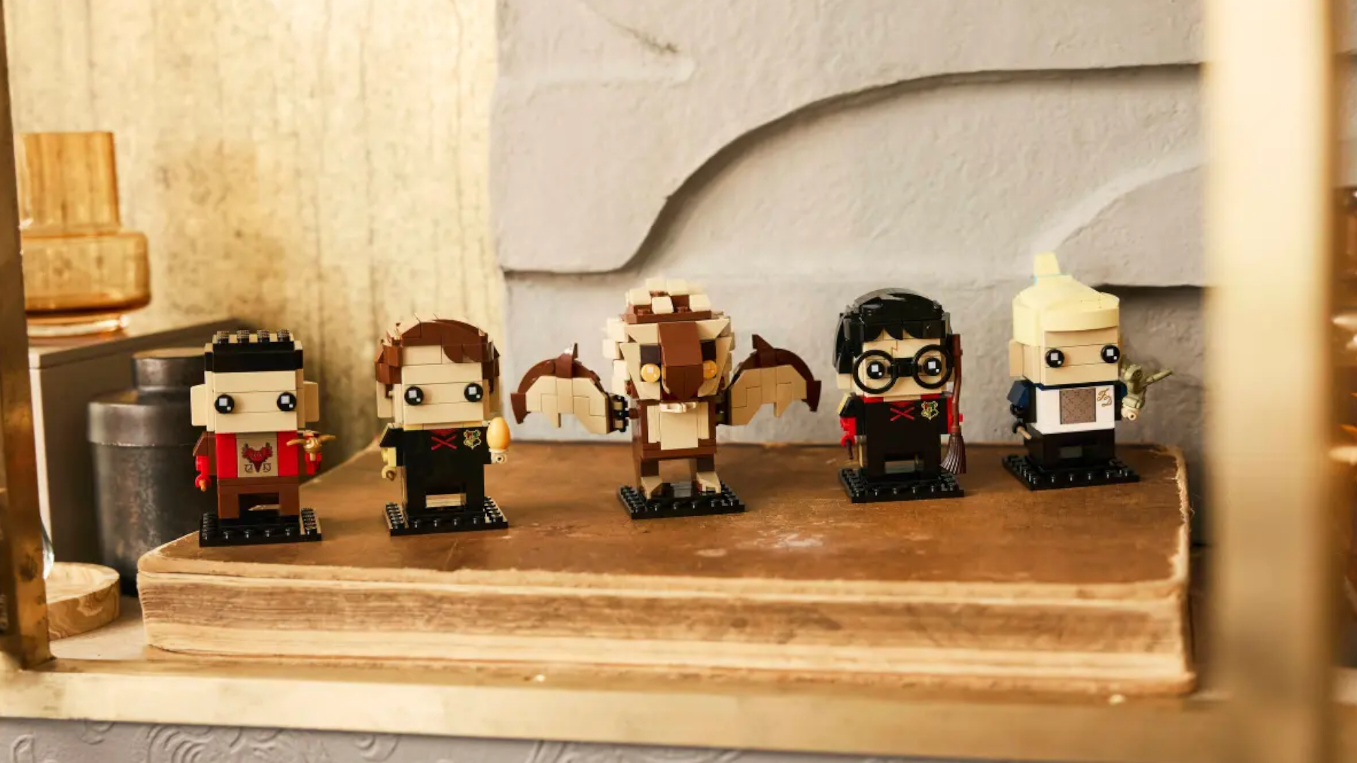 Five BrickHeadz Lego figures based on Harry Potter characters from the Goblet of Fire movie stand in a line on an old book