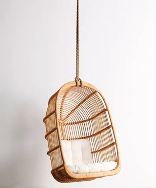 A cage-style egg chair made from rattan, manilla rope and white removable polyester cushion