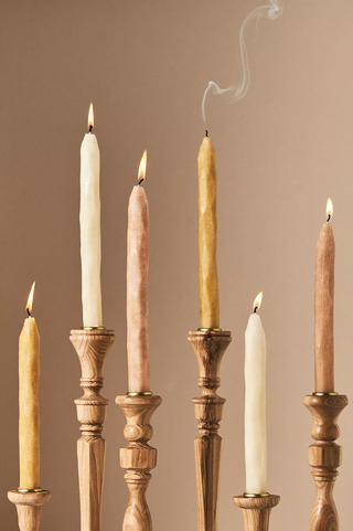 six neutral candles sitting in traditional wooden candlesticks