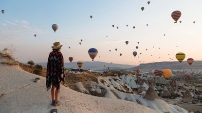 woman and hot air balloons in the evening, Goreme, Cappadocia, Turkey - stock photo