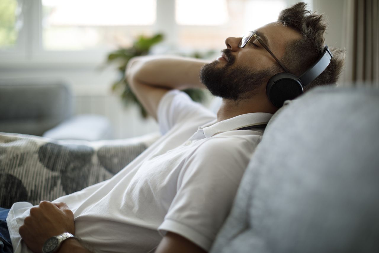 man listening to headphones on couch