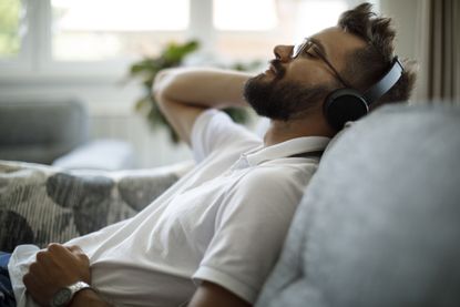 man listening to headphones on couch