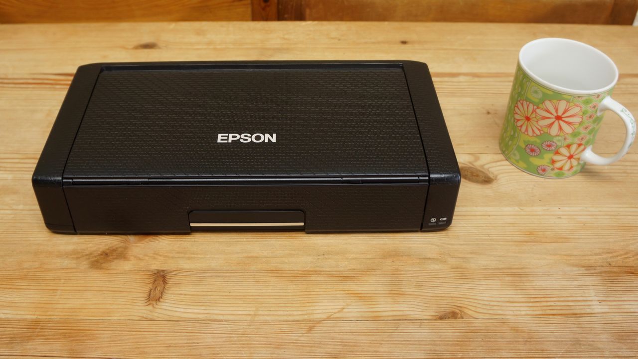 Epson WorkForce WF-110 on a table by a mug during our tests
