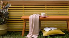 A painted wooden outdoor bench in front of painted garden fencing