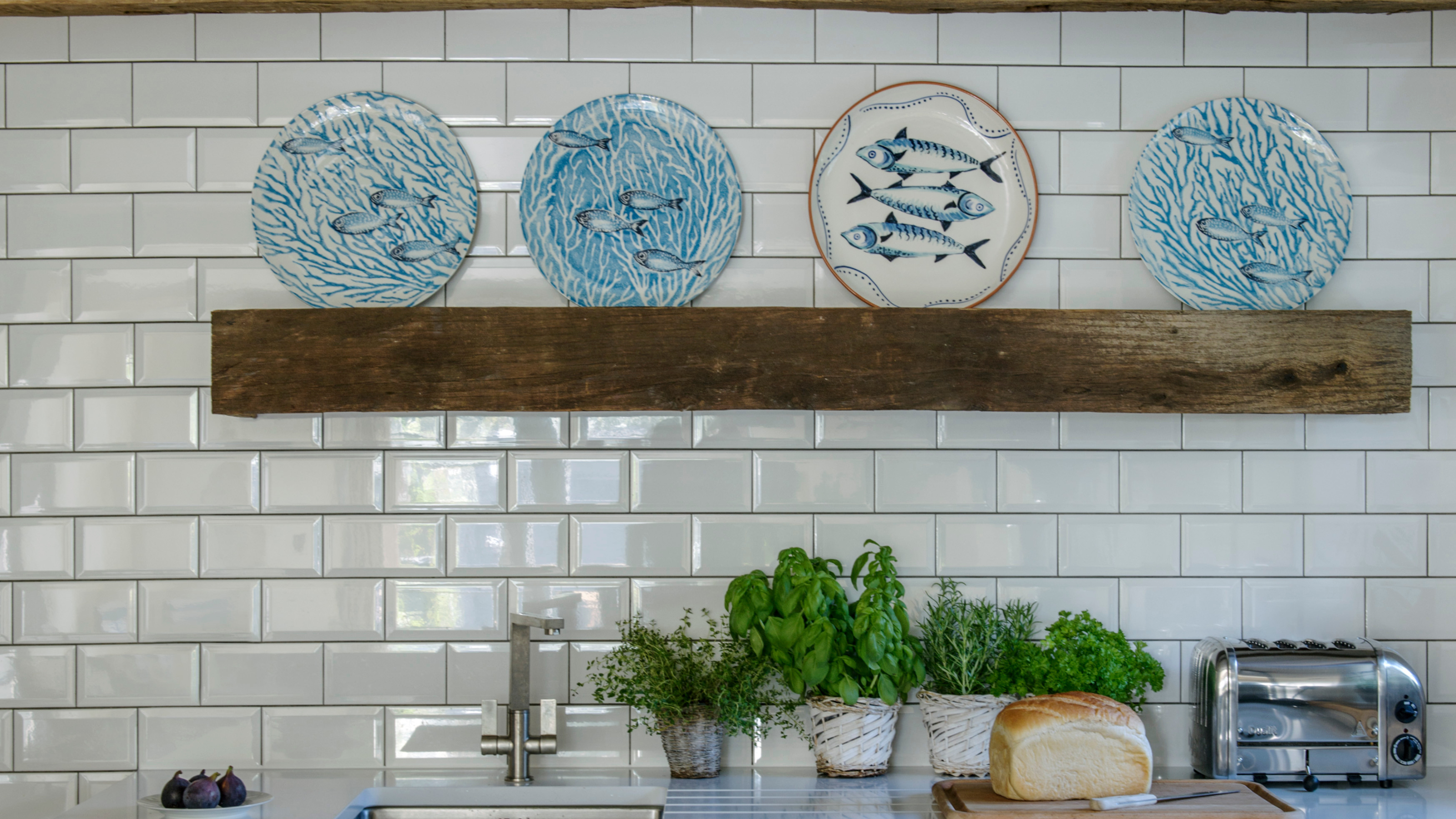 Fish plates on display on a wooden shelf in a kitchen.