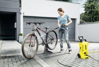 Karcher K2 pressure washer in use by an adult woman cleaning a bicycle