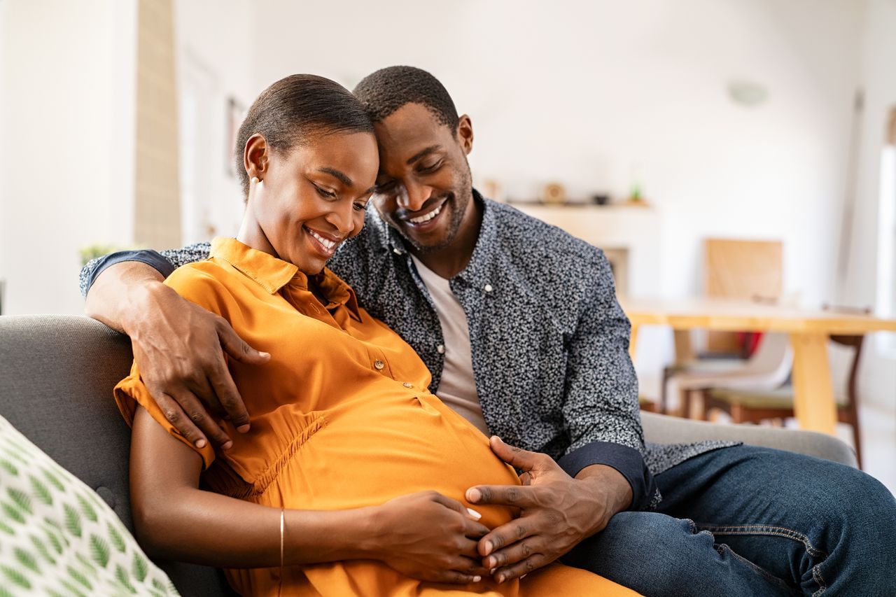 A pregnant woman sitting next to a man on a sofa