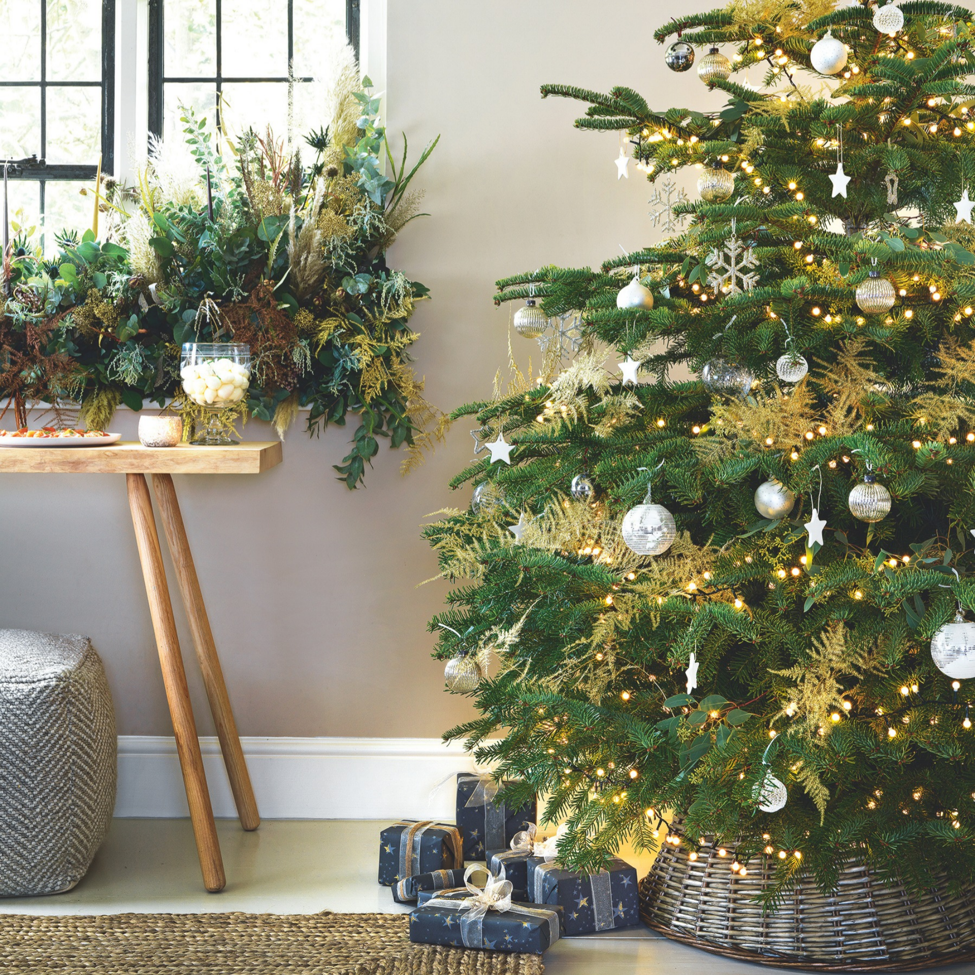 Christmas tree with woven skirt, white baubles and gold fairy lights.