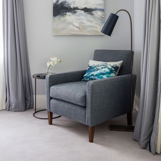 Grey armchair on carpet in front of floor light