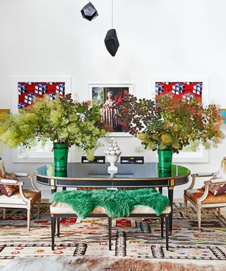 colorful dining room with black oval table, cowhide bench and chairs, green sheepskin rug, black mobile, graphic blinds and patterned rug