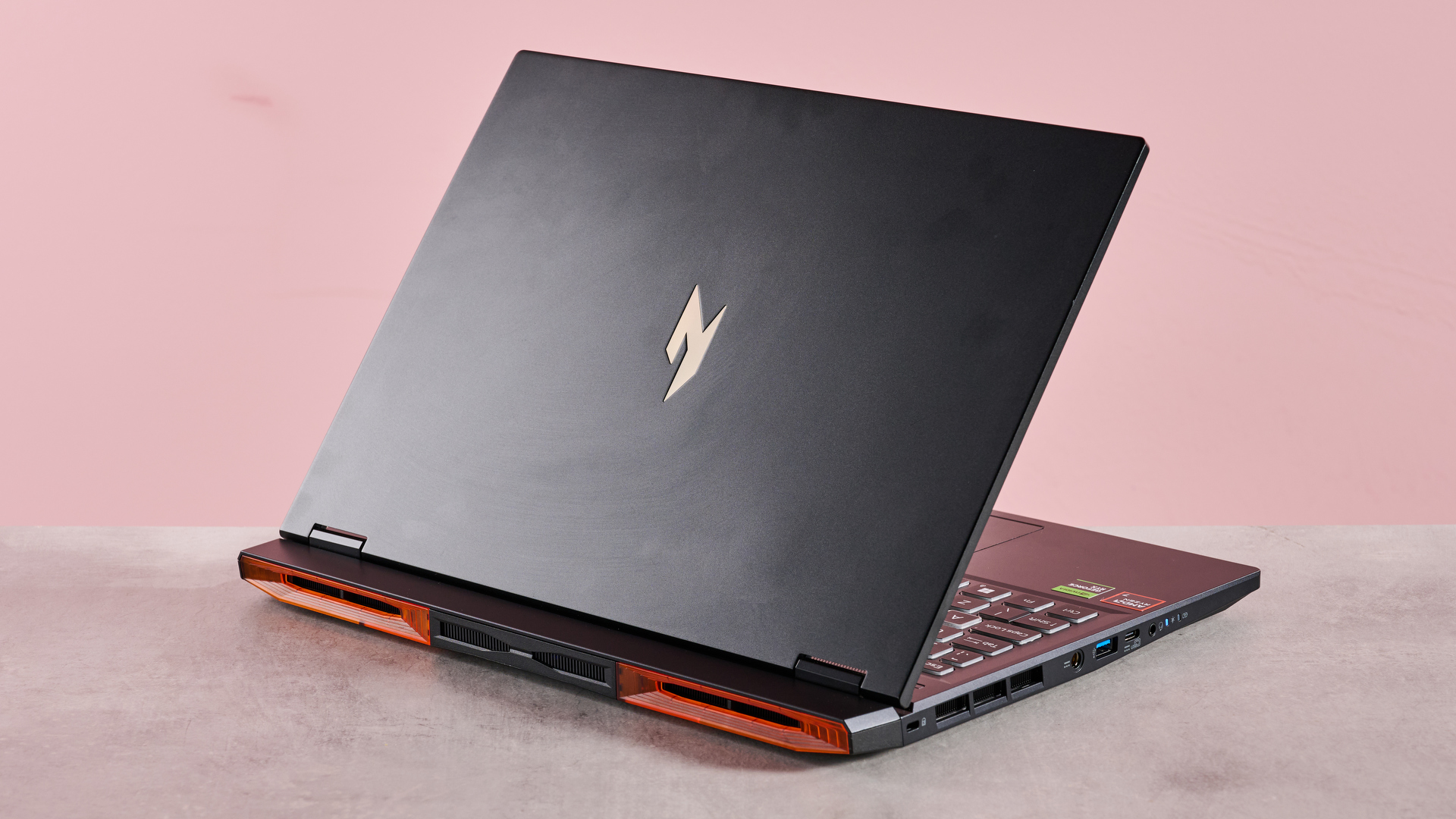 The Acer Nitro 14 compact gaming laptop photographed on a coral background.