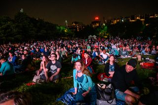 A crowd gathered on a lawn in Brooklyn Bridge Park to watch the presentations for the free event "Saturday Night Lights," held as part of the 2019 World Science Festival on June 1.