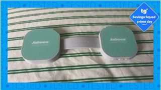 The Jabees PEACE Duo Pillow Speaker on striped bedding. A border shows the word "TESTED" in a repeated pattern. A Amazon Prime Day deals badge is seen in the top right foreground. 