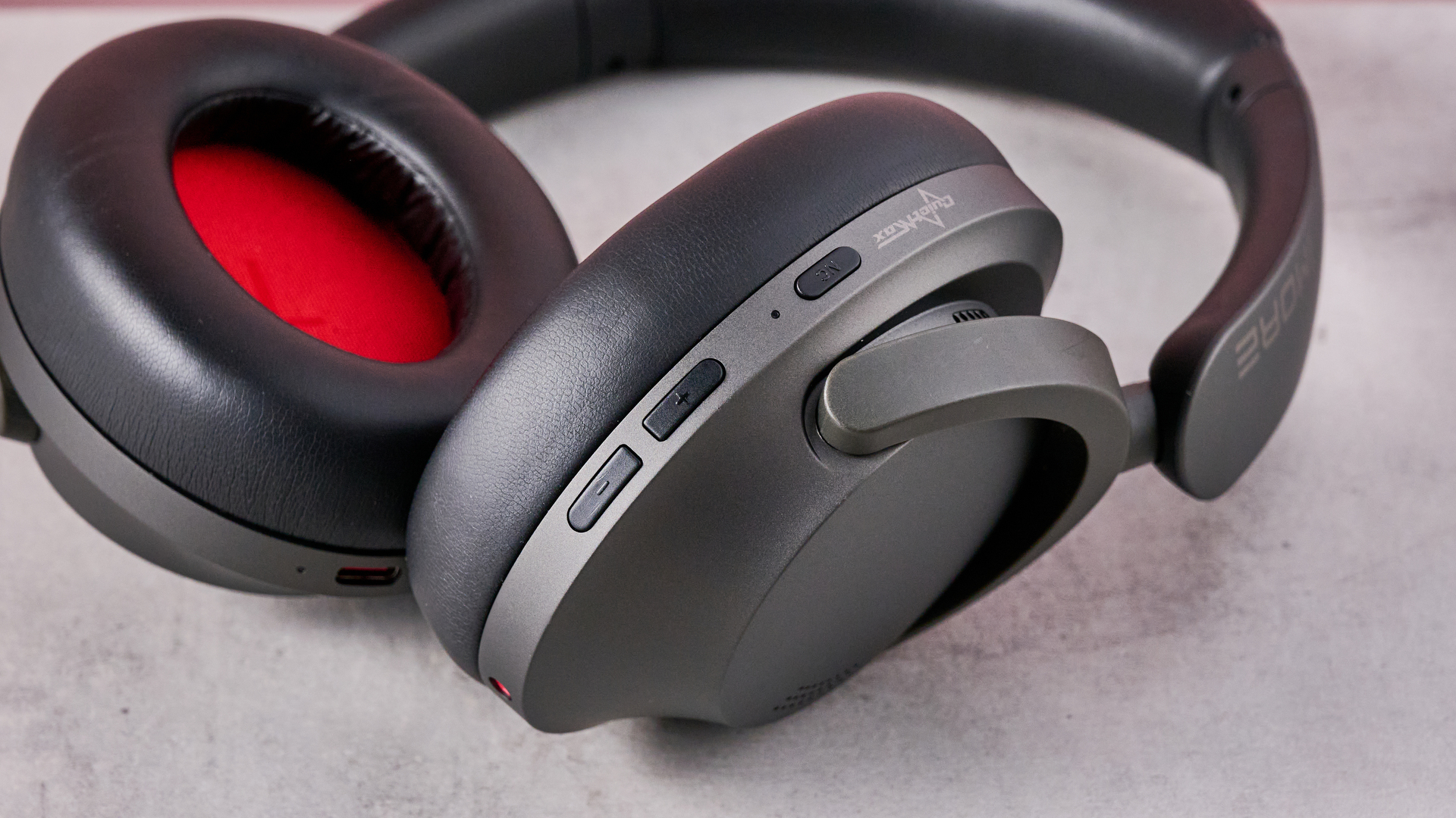 1More SonoFlow Pro HQ51 headphones on a gray surface with a pink background showing the controls on the earcup