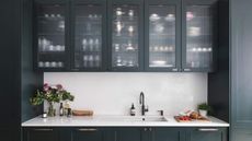 A navy kitchen with frosted glass cabinets