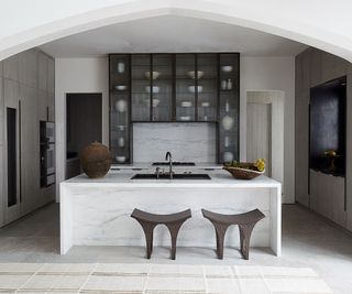 Kitchen with white walls and black bar stools and a black textured cupboard in the back