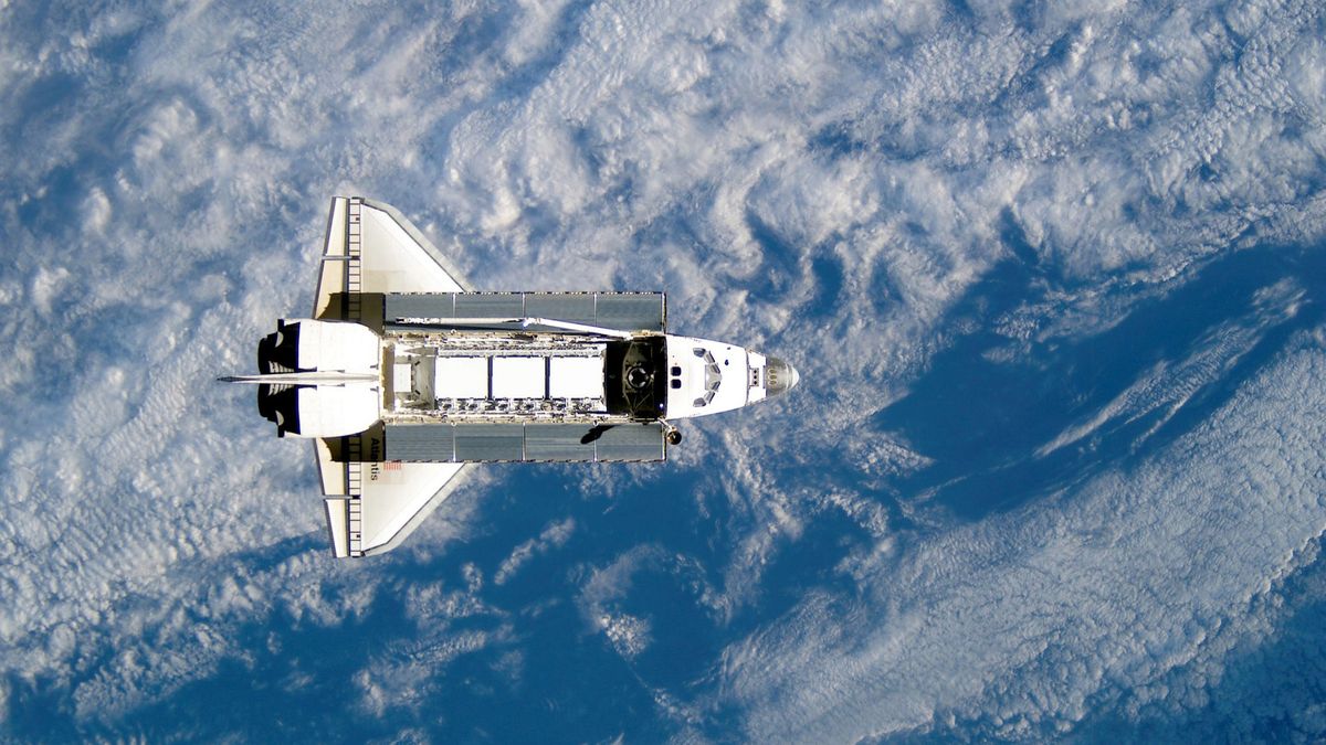 Space Shuttle Atlantis backdropped against a blue and white Earth