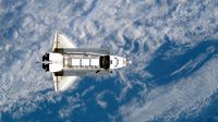 Space Shuttle Atlantis backdropped against a blue and white Earth