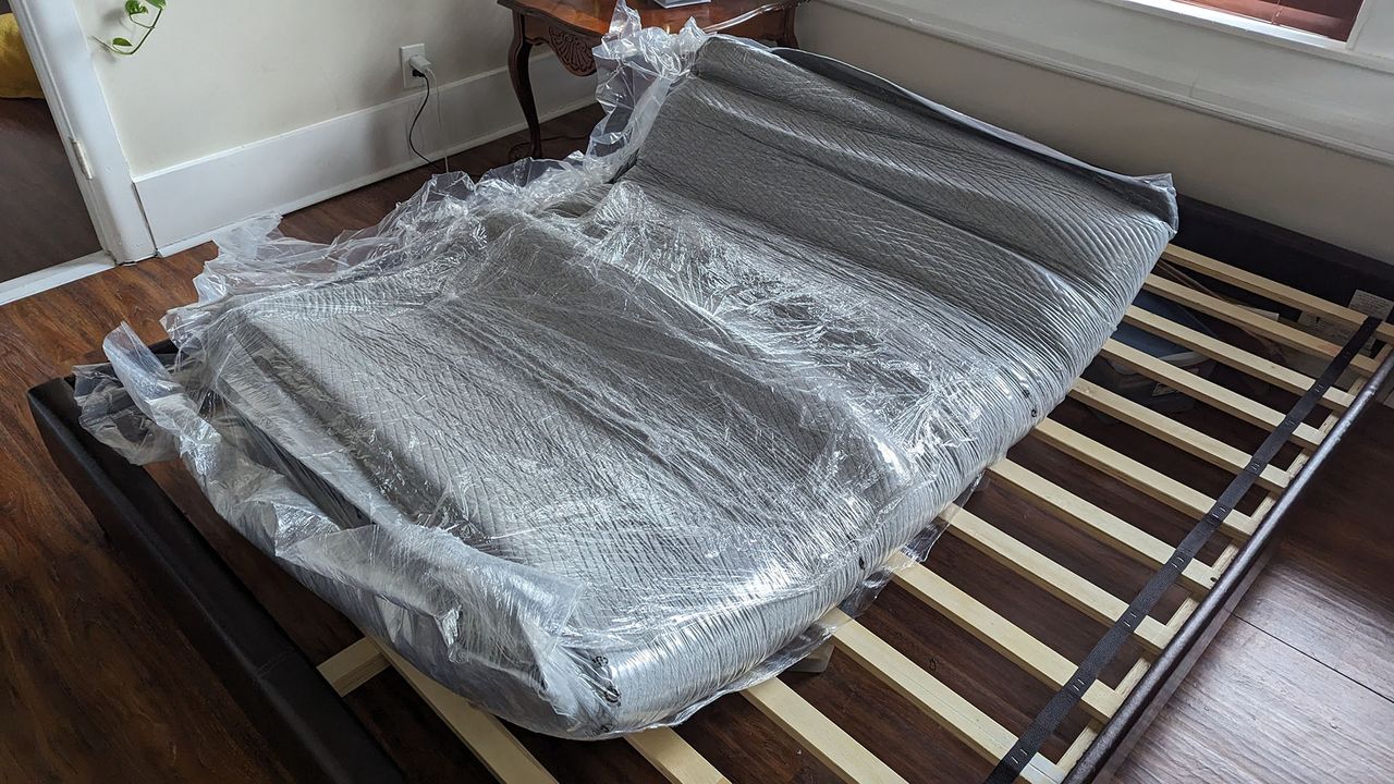 Casper Original mattress in its plastic wrapping on a bed frame