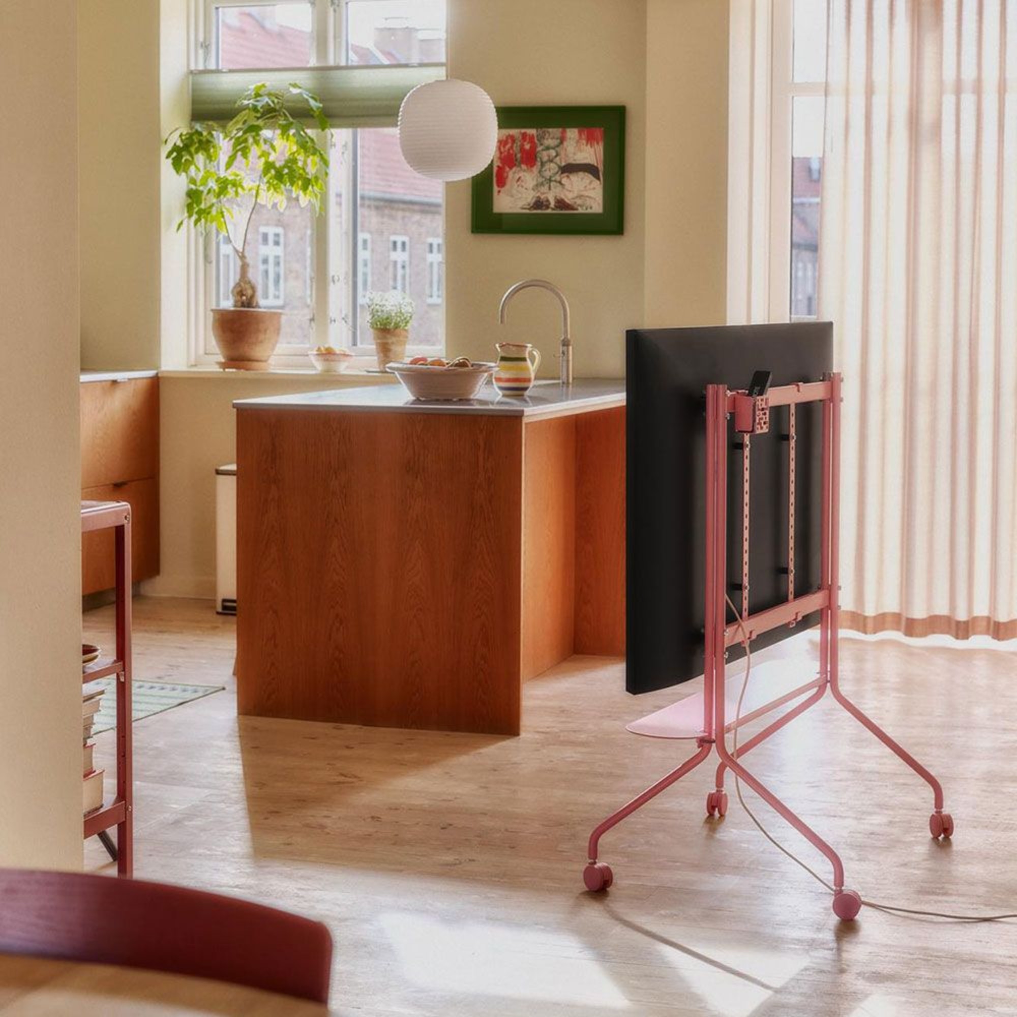 Pedestal Moon Rollin' TV Stand in pink in an open-plan wooden kitchen painted in butter yellow