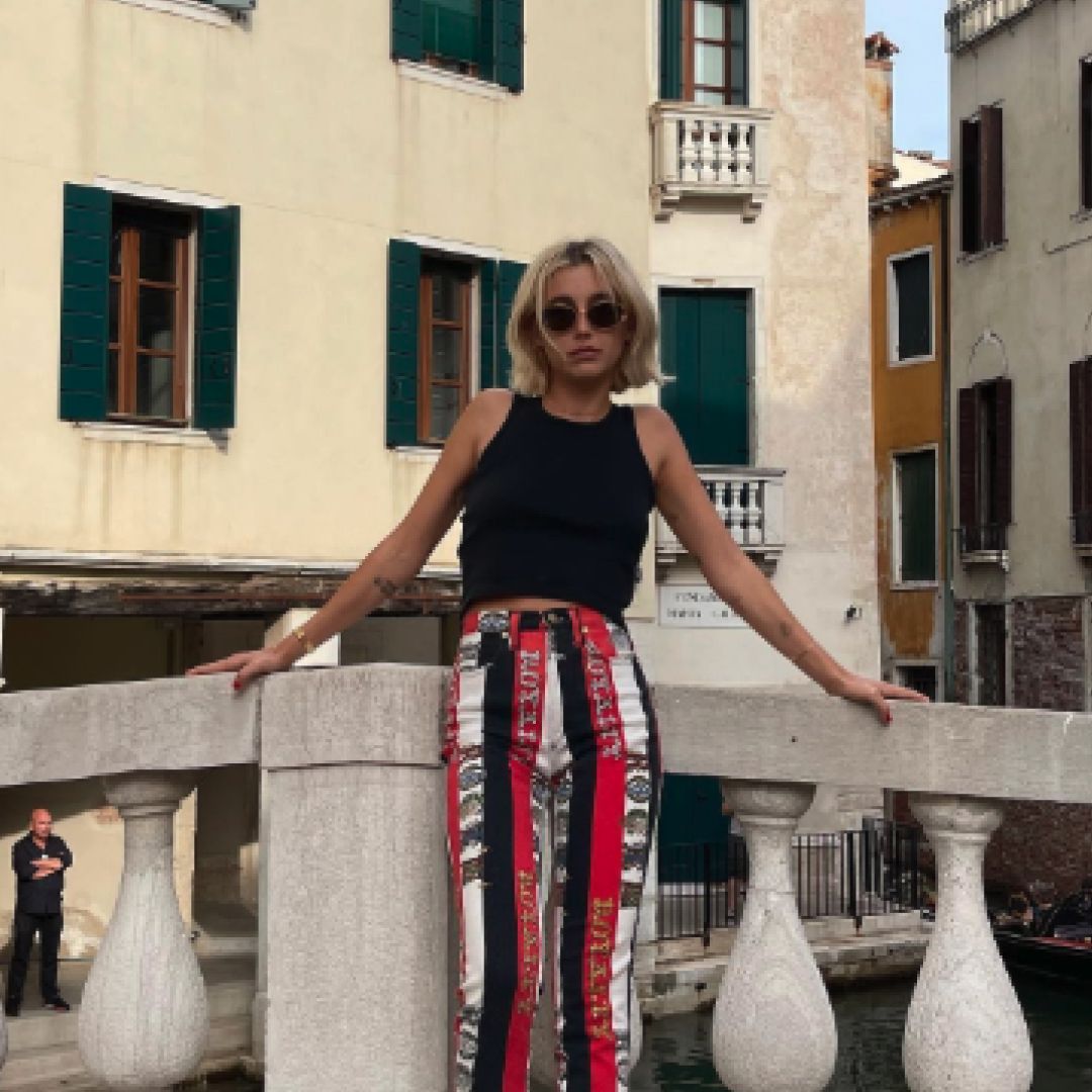 Emma Chamberlain wearing striped Versace jeans with a tank top in a snippet of her closet sale