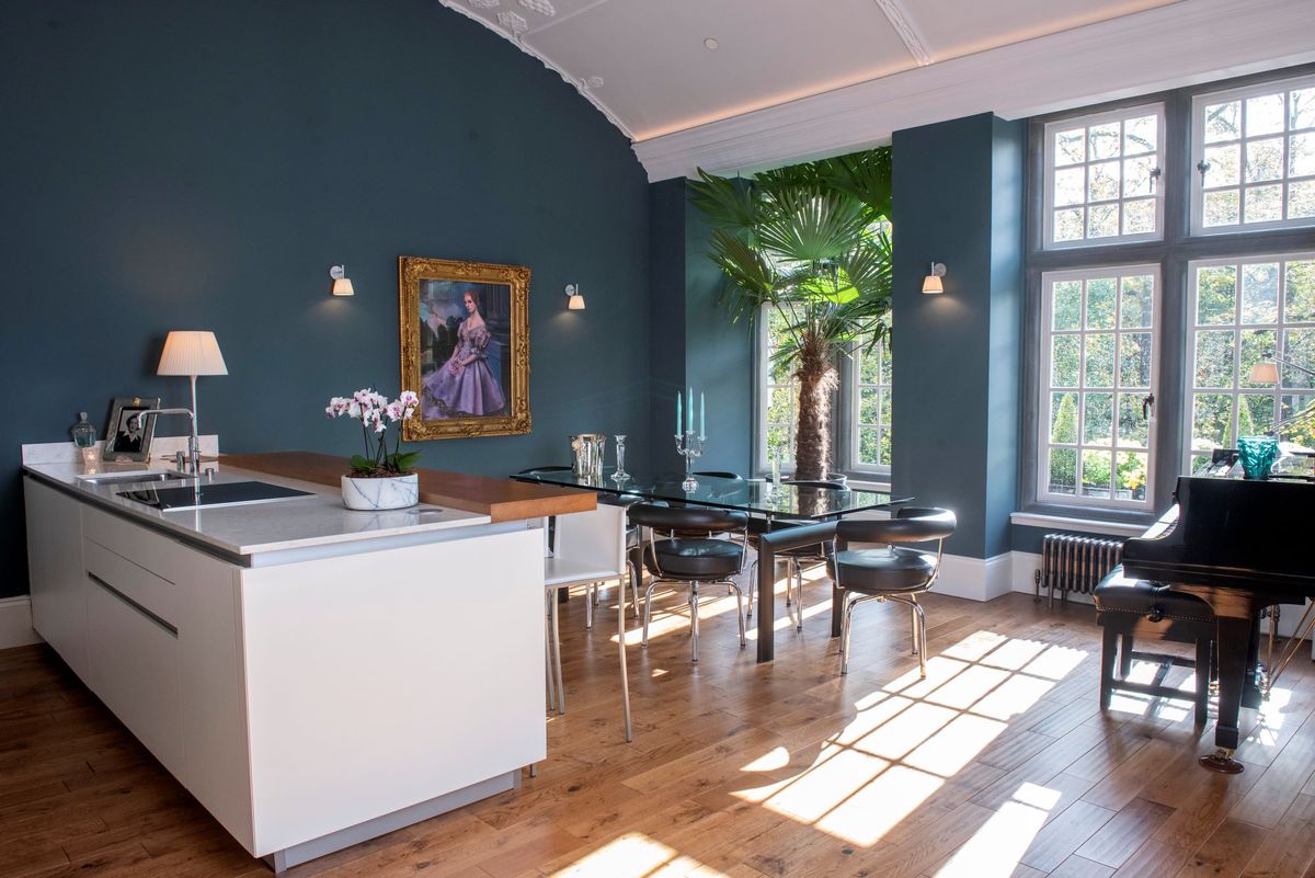The kitchen-diner shows a kitchen island with induction hob with a dining area and glass table which leads to the balcony