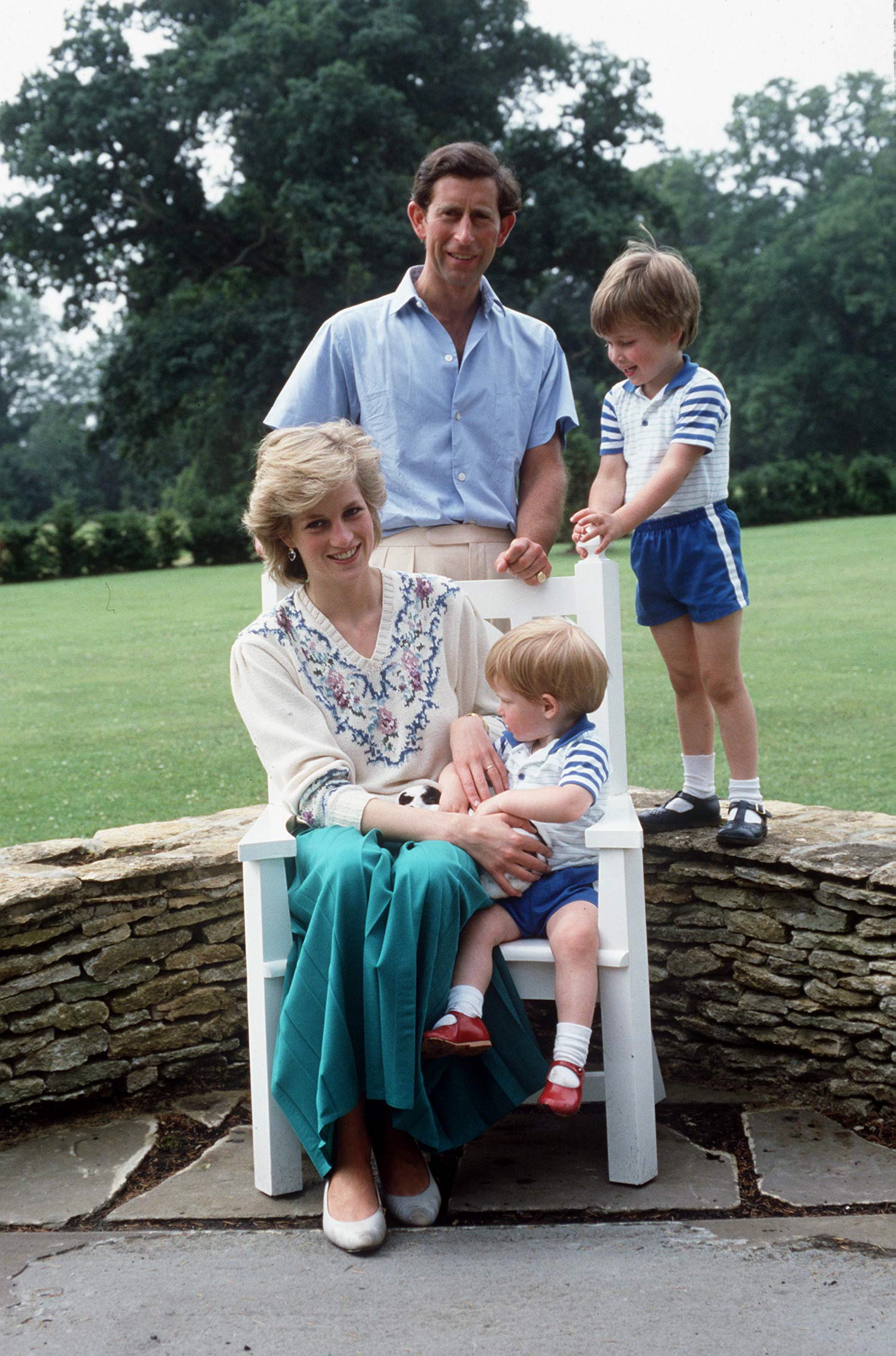 Princess Diana, Prince Charles, Prince Harry and Prince William in 1986 sitting on a stone wall