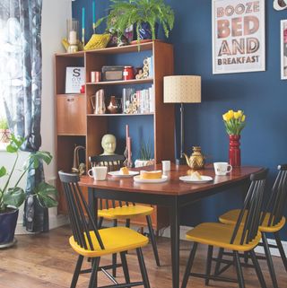 eclectic blue dining room with wood chairs with yellow seats