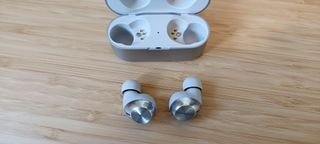 A pair of silver Technics EAH-AZ40M2 earphones on a wooden table