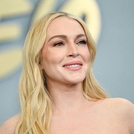 lindsay lohan poses on a red carpet at a disney event