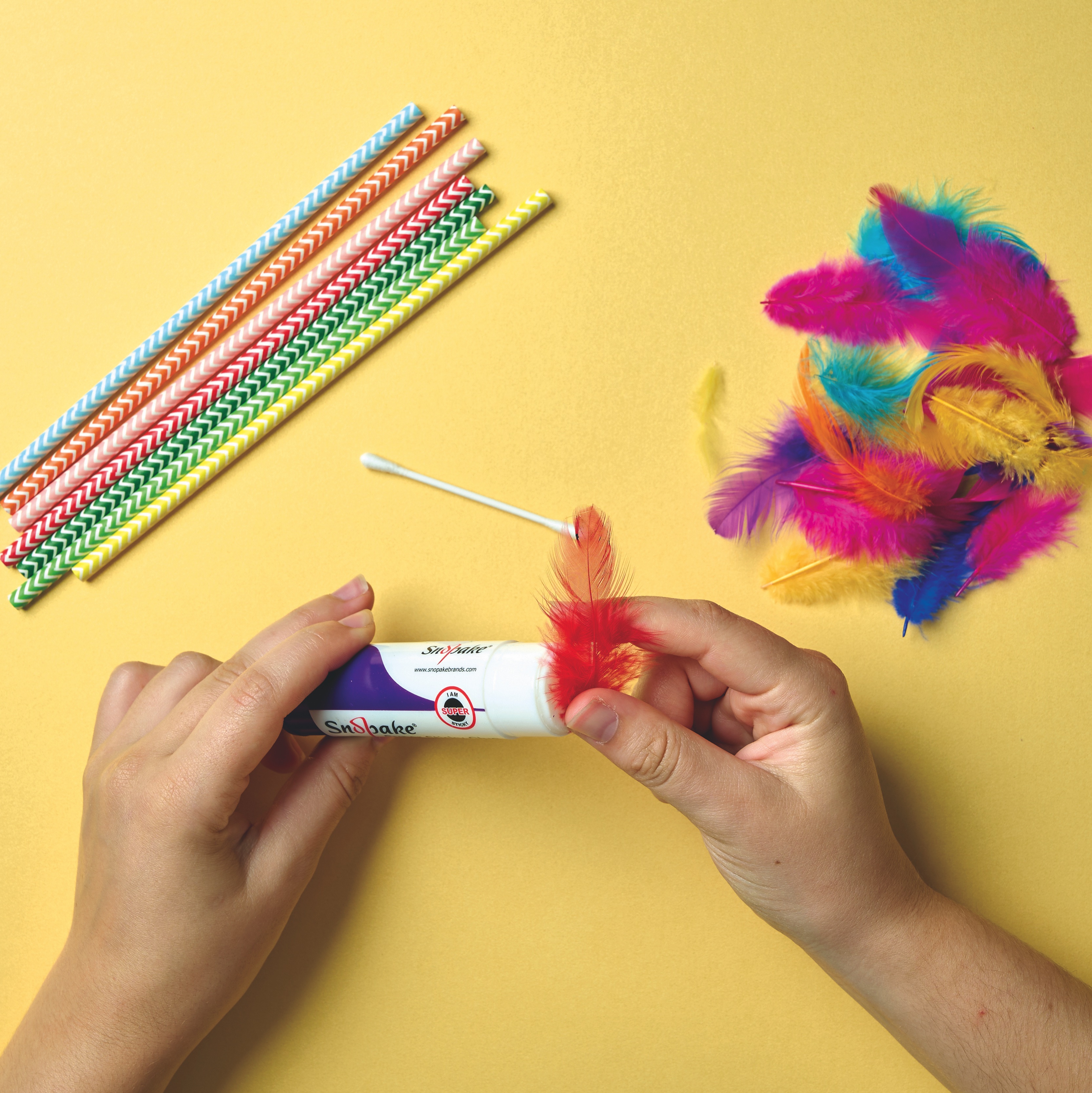 Using glue to make a blow dart out of straw and feathers