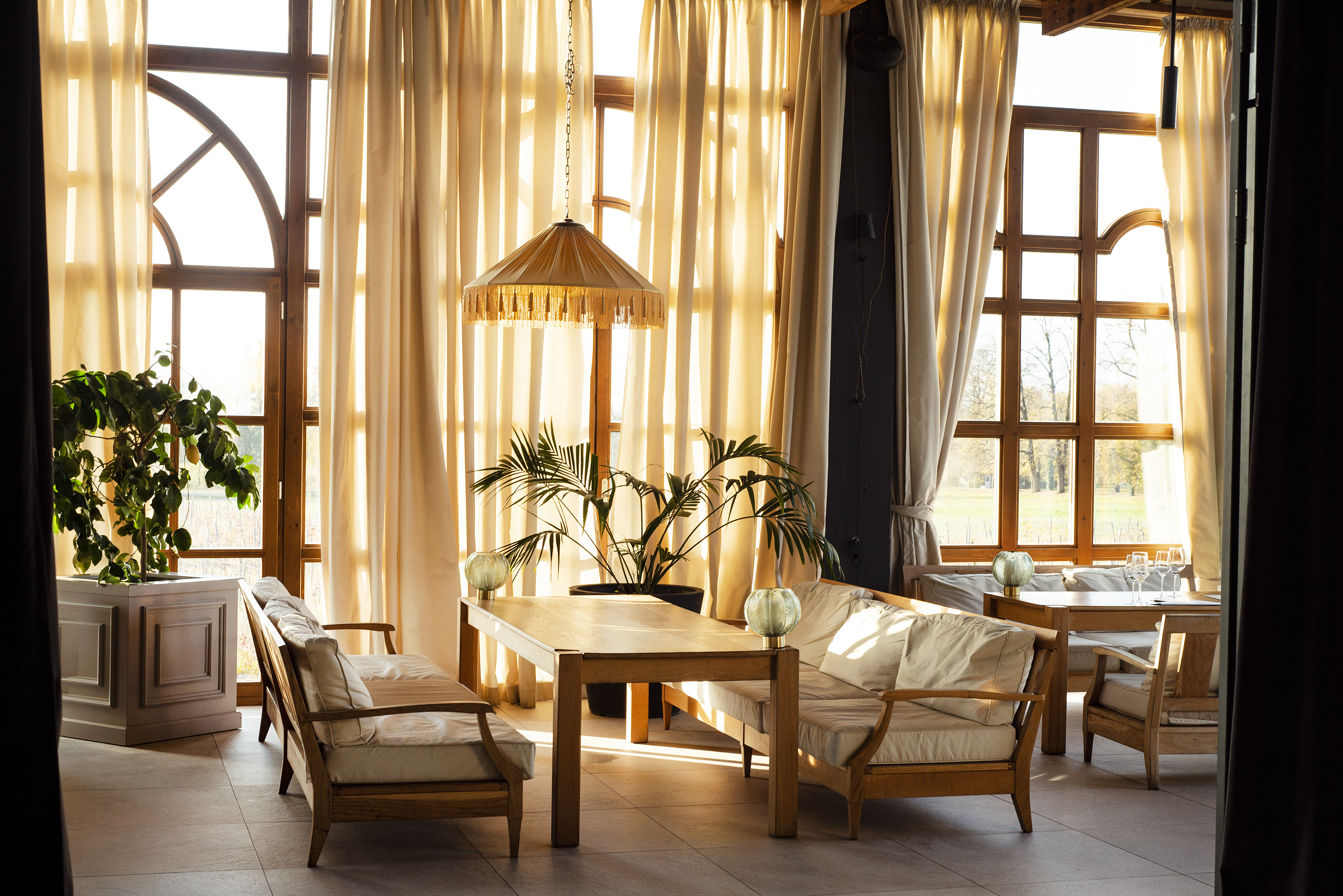 A series of pictures depicting the interior and exterior grounds of a sprawling resort, immersed in nature, between vineyards, gardens, and spa pools, and decorated with crafty artifacts.