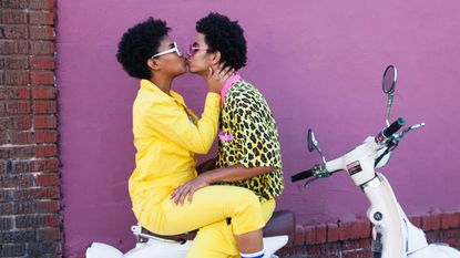 couple kissing on the back of a scooter - stock photo