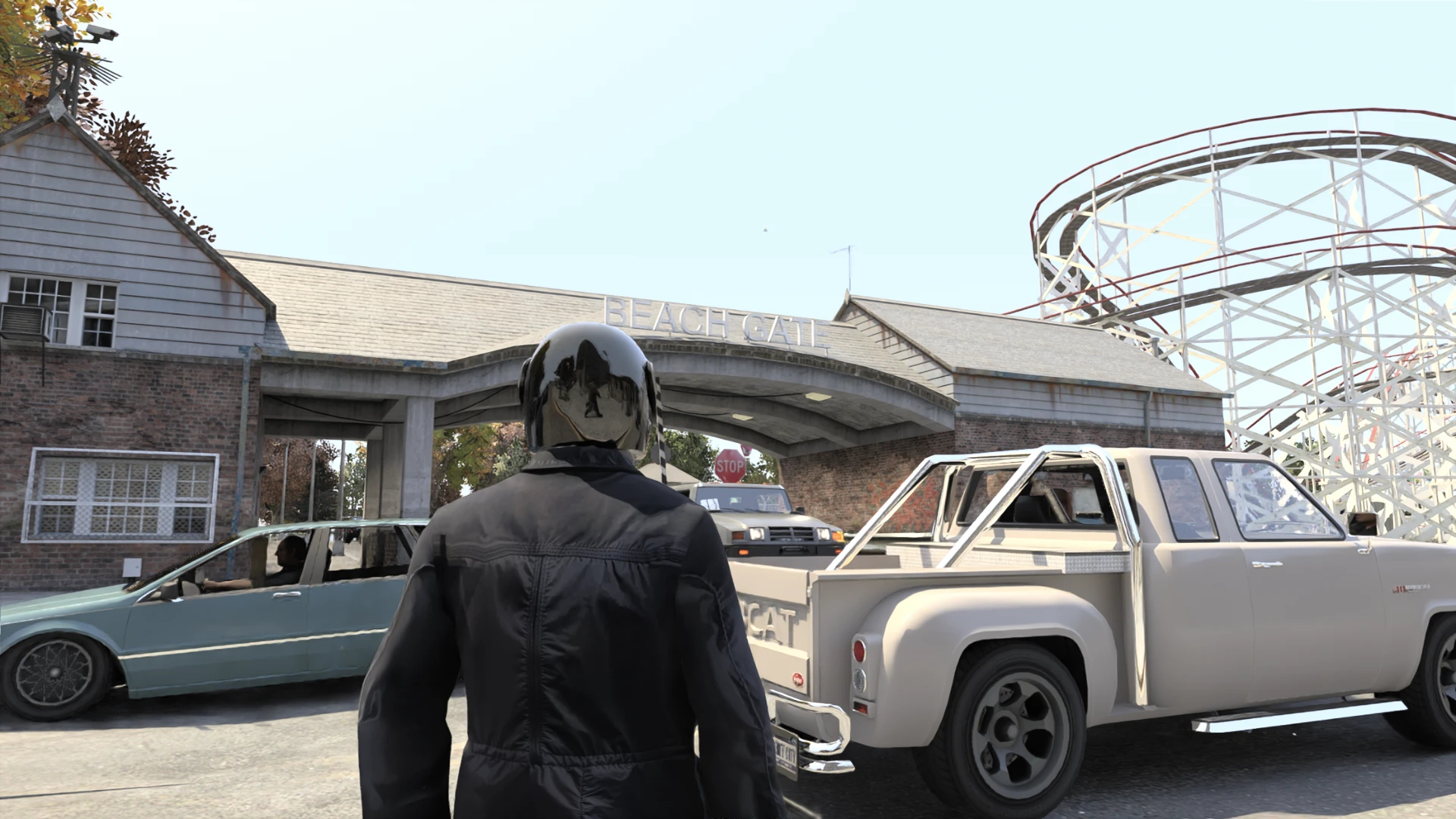 A GTA IV character in a dark jacket and motorcycle helmet standing in front of cars, with a roller coaster in the background.