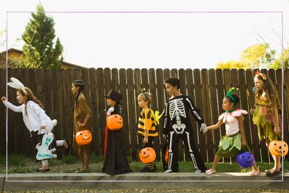 Kids celebrating Halloween by wearing costumes and standing in a line