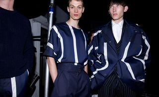 Three guys wearing E Tauts S/S 2015 collection. The guy on the left is wearing a navy jersey and navy and white striped pants. The guy n the middle is wearing a navy and white striped shirt with navy pants and the guy on the right is wearing a white shirt and a navy striped suit with a navy and white striped jacket over his suit