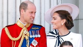 Prince William and Catherine, Princess of Wales smile at each other as they watch an RAF flypast from the balcony of Buckingham Palace after attending Trooping the Colour on June 15, 2024