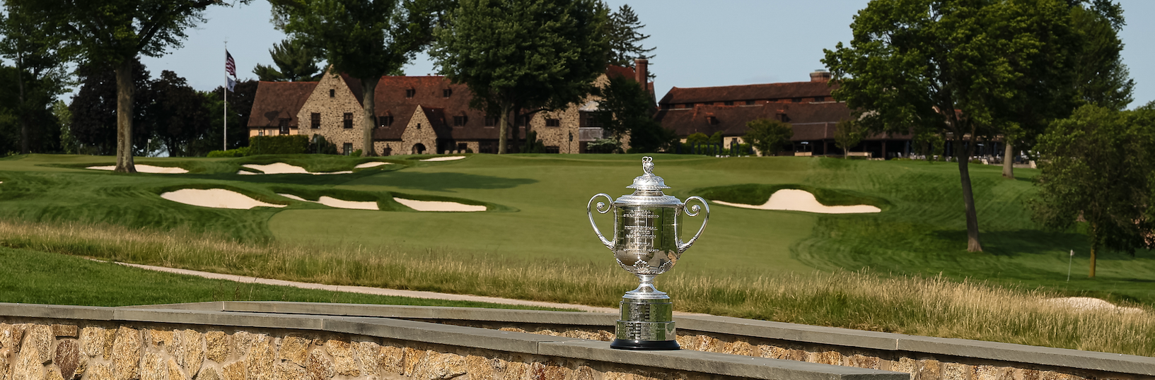 The PGA Championship Wanamaker Trophy sitting on a bridge in front of the Aronimink clubhouse