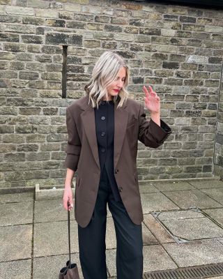 Woman wears brown blazer, black waistcoat and black tailored trousers